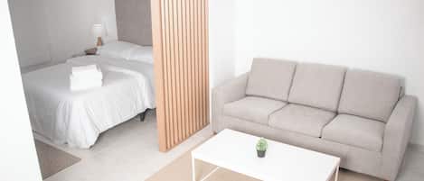 Une chambre d’hôtel moderne équipée d’un lit, d’un canapé, d’une table basse et d’une cloison en bois.