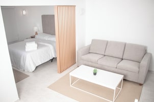Una habitación de hotel moderna con una cama, un sofá, una mesita de café y un separador de madera.