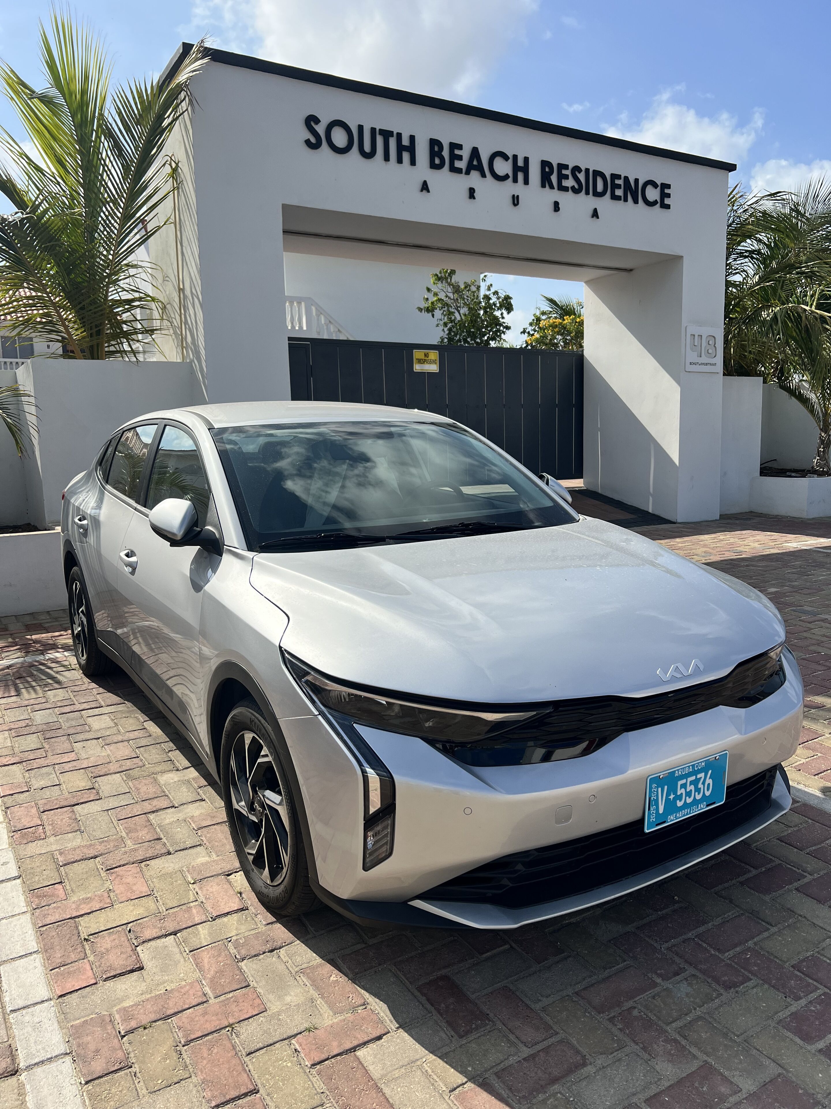 A white Kia sedan parked in front of a building labeled "South Beach Residence."