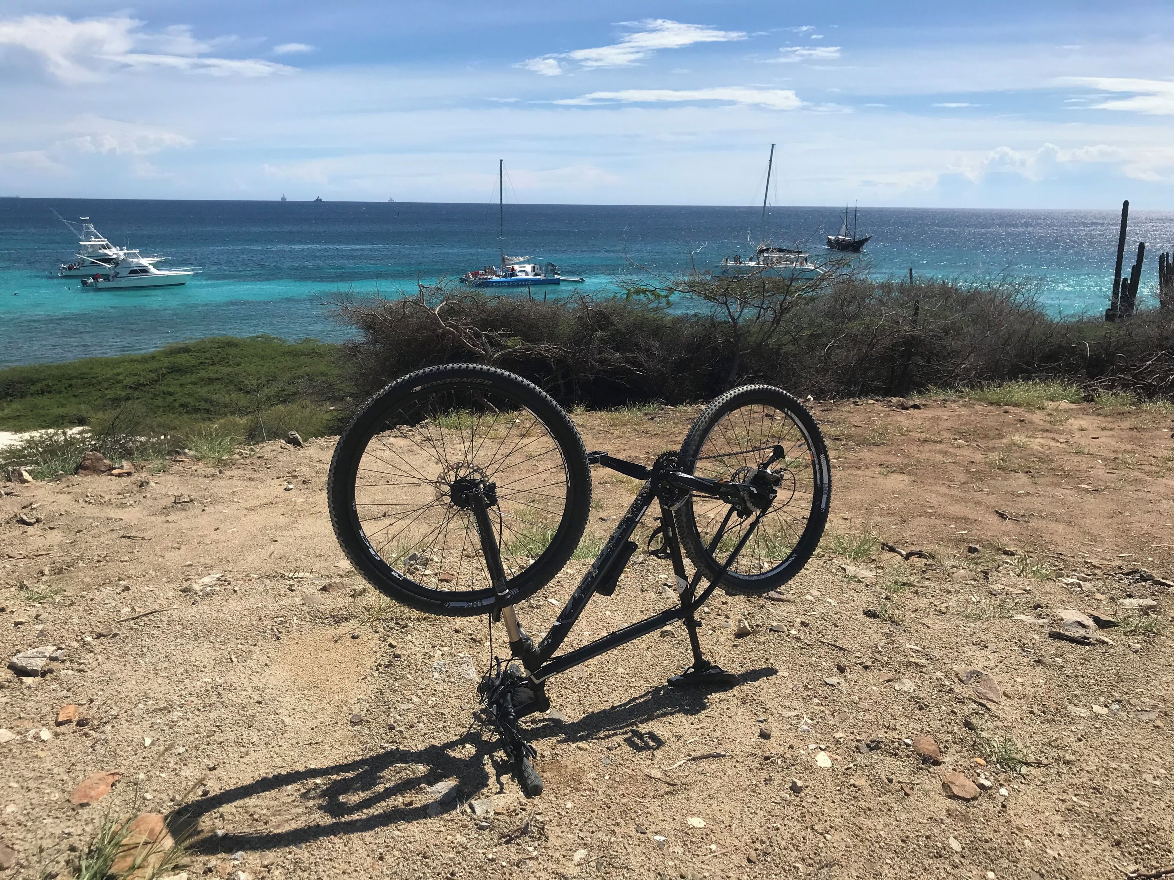 Una bicicleta estacionada en un sendero de tierra con vista al océano y barcos.