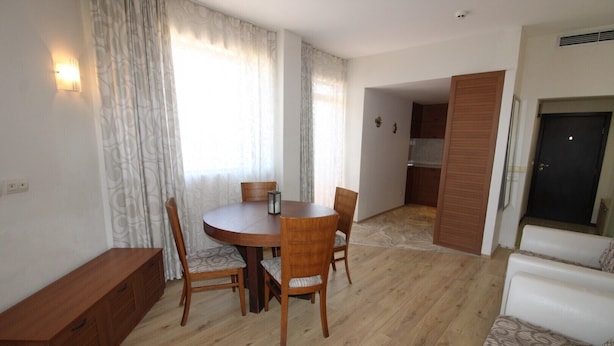 A room with a round wooden dining table, four chairs, a bench, and a sofa. - Menada Vris Apartments (Tsarevo)