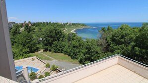A balcony with a view of a coastal area, including a beach and a swimming pool. - Menada Vris Apartments (Tsarevo)