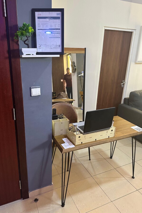 A room with a desk, a laptop, a small plant, and a framed certificate on the wall.