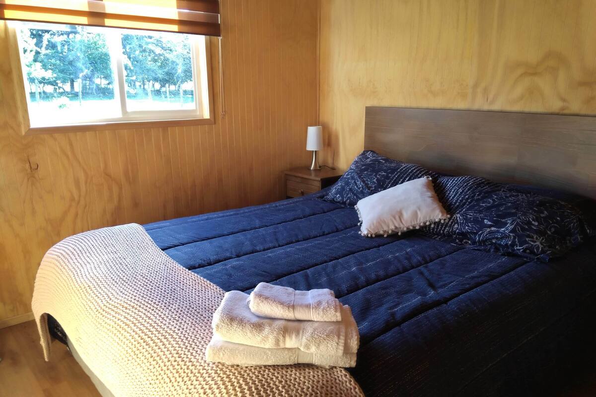 Ein ordentlich gemachtes Bett mit einer blauen Steude, einem weißen Kopfkissen und einer beigen Decke.