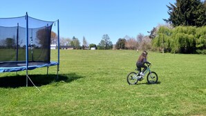 Un champ d’herbe avec un trampoline et un cycliste.