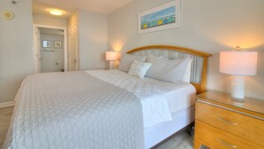 Une chambre à coucher avec un lit, des lampes de chevet, une table de nuit en bois, un ventilateur de plafond et un tableau au mur.