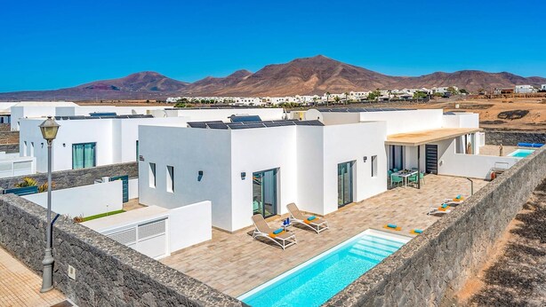 Un hôtel moderne doté d’une piscine sur le toit, d’une architecture blanche et offrant une vue sur les montagnes.