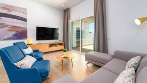 Un salon moderne avec un grand téléviseur à écran plat, un canapé bleu, un canapé gris et une table basse en bois.