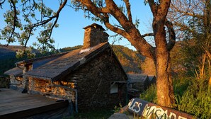Ein rustikales Steinhaus mit einer Holzterrasse, einem Schornstein und einem Schild mit der Aufschrift 'LES MASAQUES'.