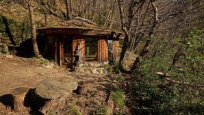 Eine rustikale Holzhütte mit einem strohgedeckten Dach, umgeben von dichtem Wald.