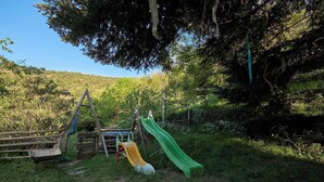 Ein Spielplatz mit Rutsche und Klettergerüsten in einem bewaldeten Gebiet.