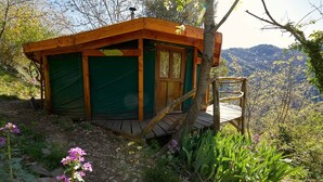 A wooden cabin with a green door, a wooden deck, and a chair. - Cévennes yurt (Malons-et-Elze)