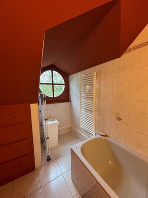 Enjoy a relaxing soak in the bathtub with a view of lush greenery.