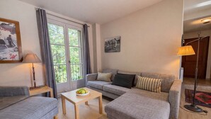 Un salon avec un canapé, une petite table sur laquelle se trouvent des fruits, une lampe et un tableau accroché au mur.