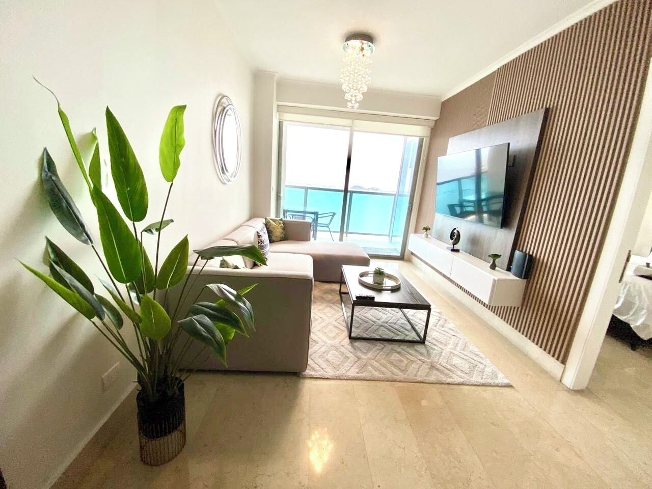 A modern living room with a sofa, coffee table, and a large TV.
