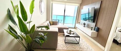 A modern living room with a sofa, coffee table, and a large TV.