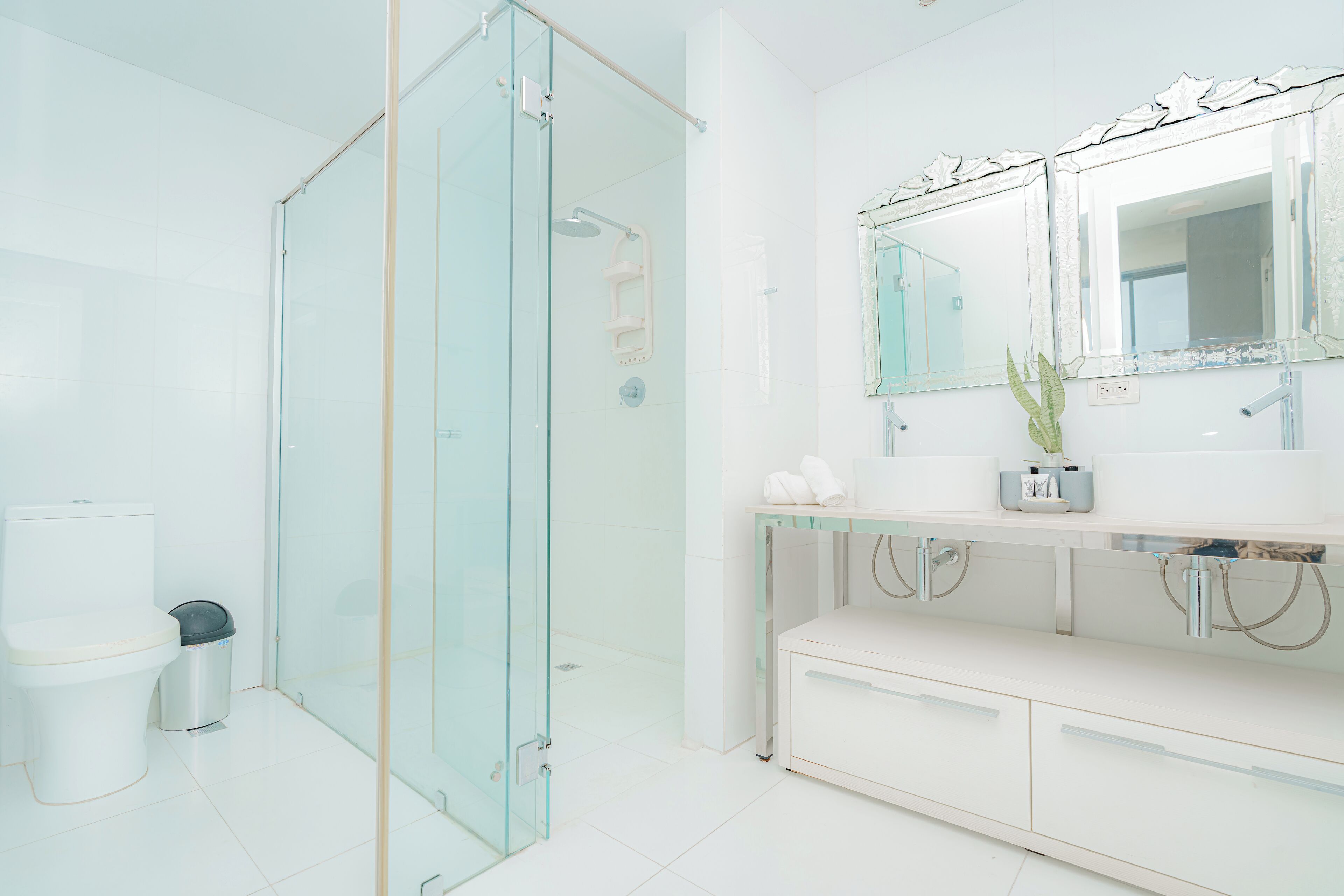 A modern bathroom with a glass shower enclosure, a white toilet, and a vanity with a mirror and sink.