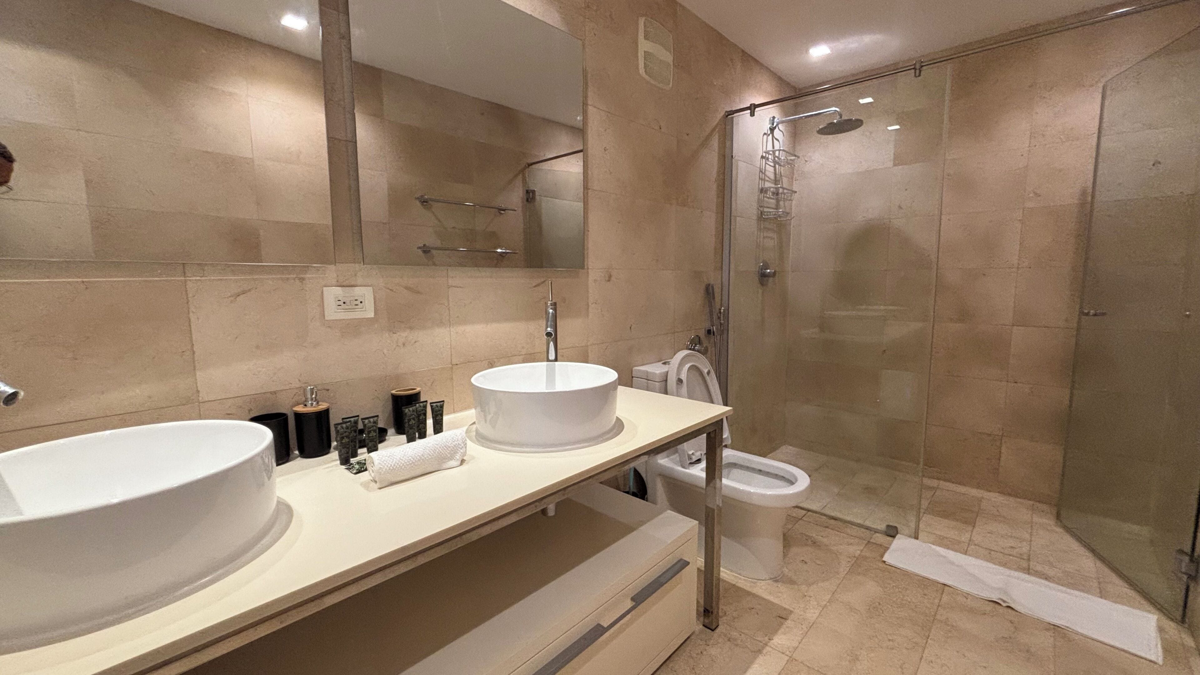 Un bagno moderno con un lavandino bianco grande, un box doccia in vetro e un water.