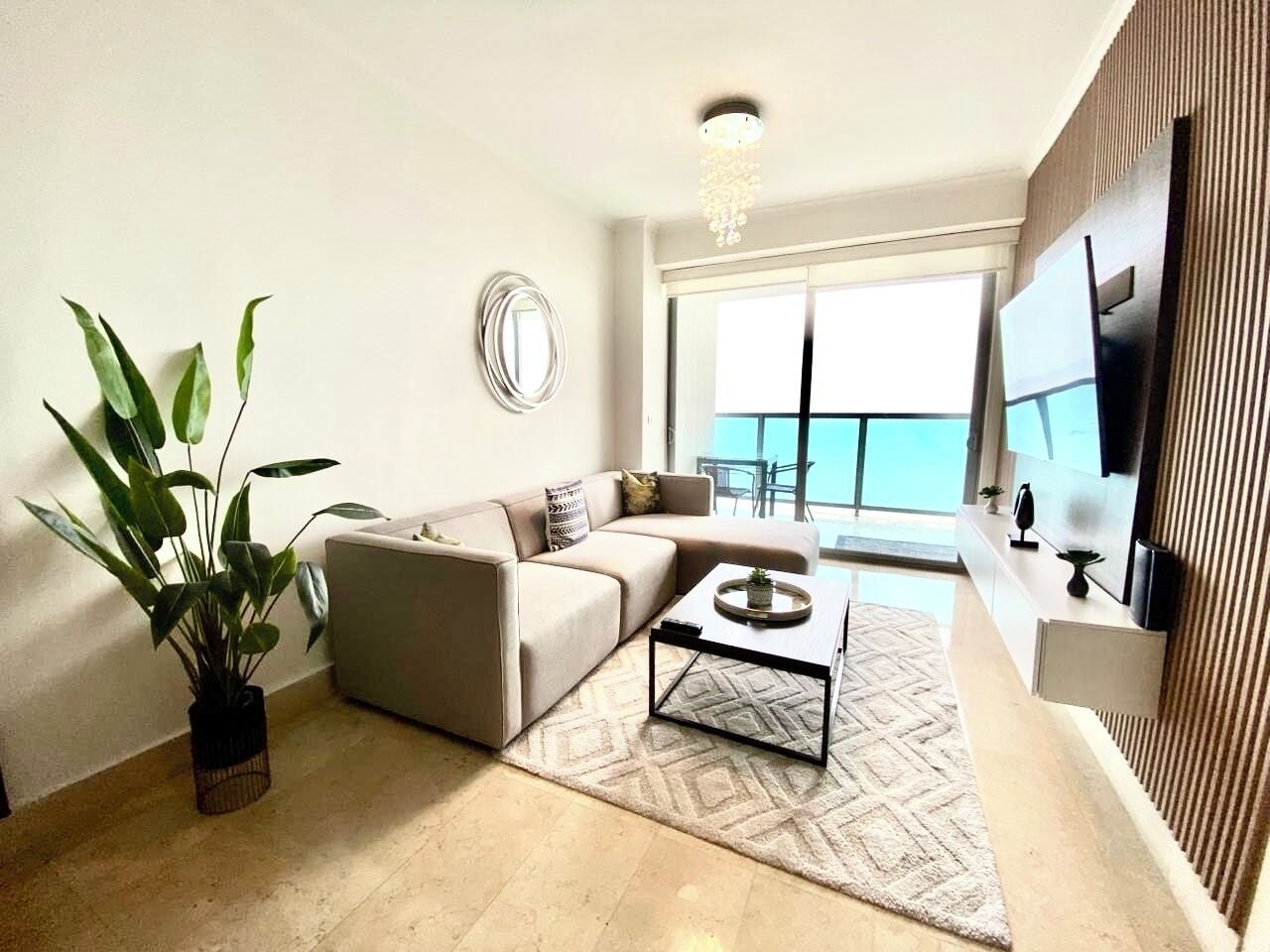 A modern living room with a sofa, coffee table, and a large window with a view.