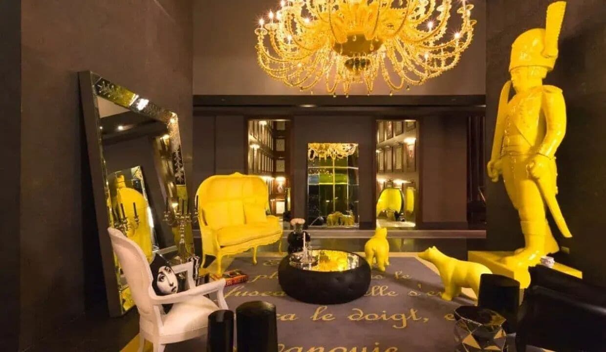 Ein luxuriöses Zimmer mit einem großen Spiegel, einem gelben Sessel, einem runden schwarzen Couchtisch und einer Statue eines Soldaten.