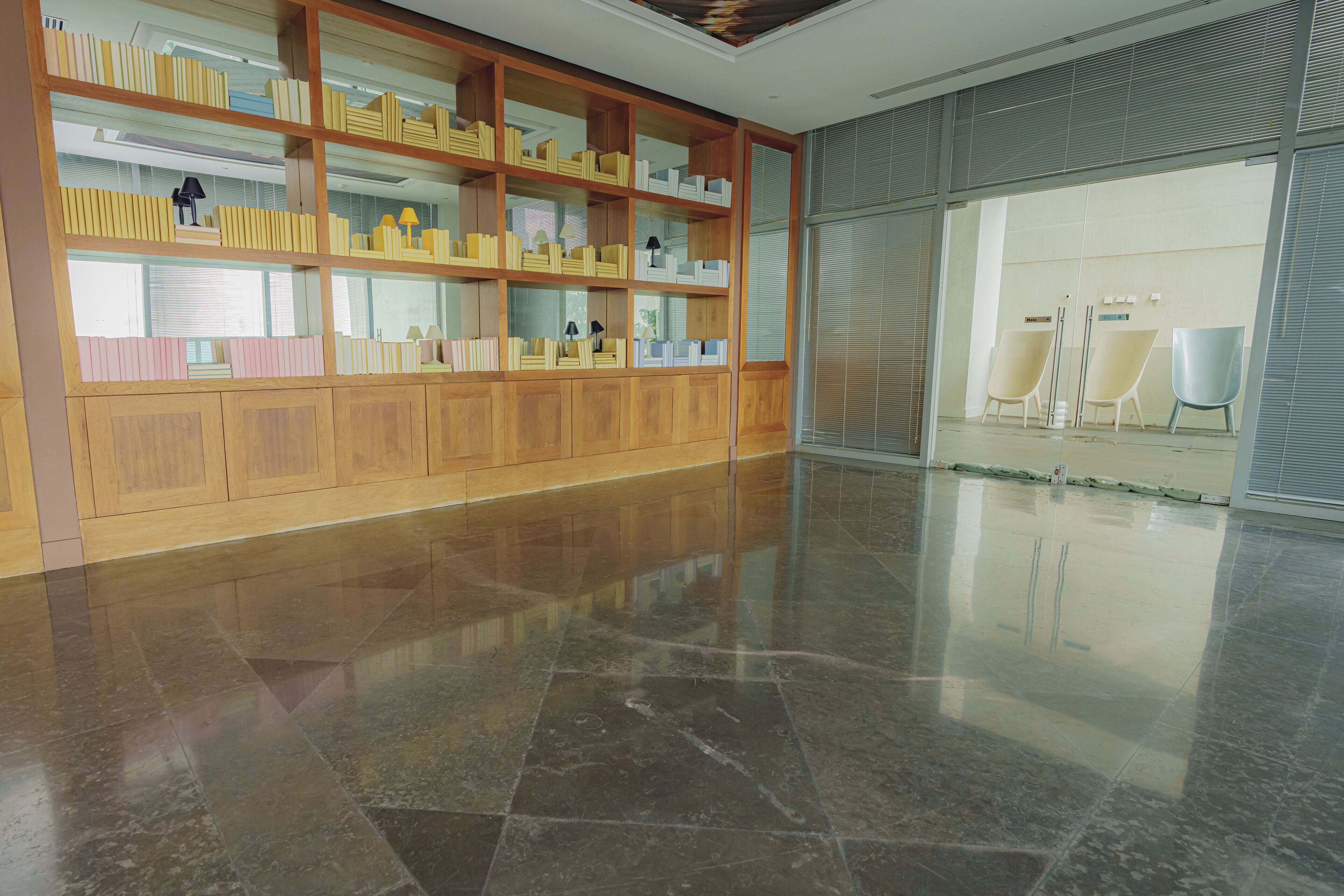 Um hall amplo com piso de mármore polido, estantes de madeira e um espaço de estar com cadeiras.