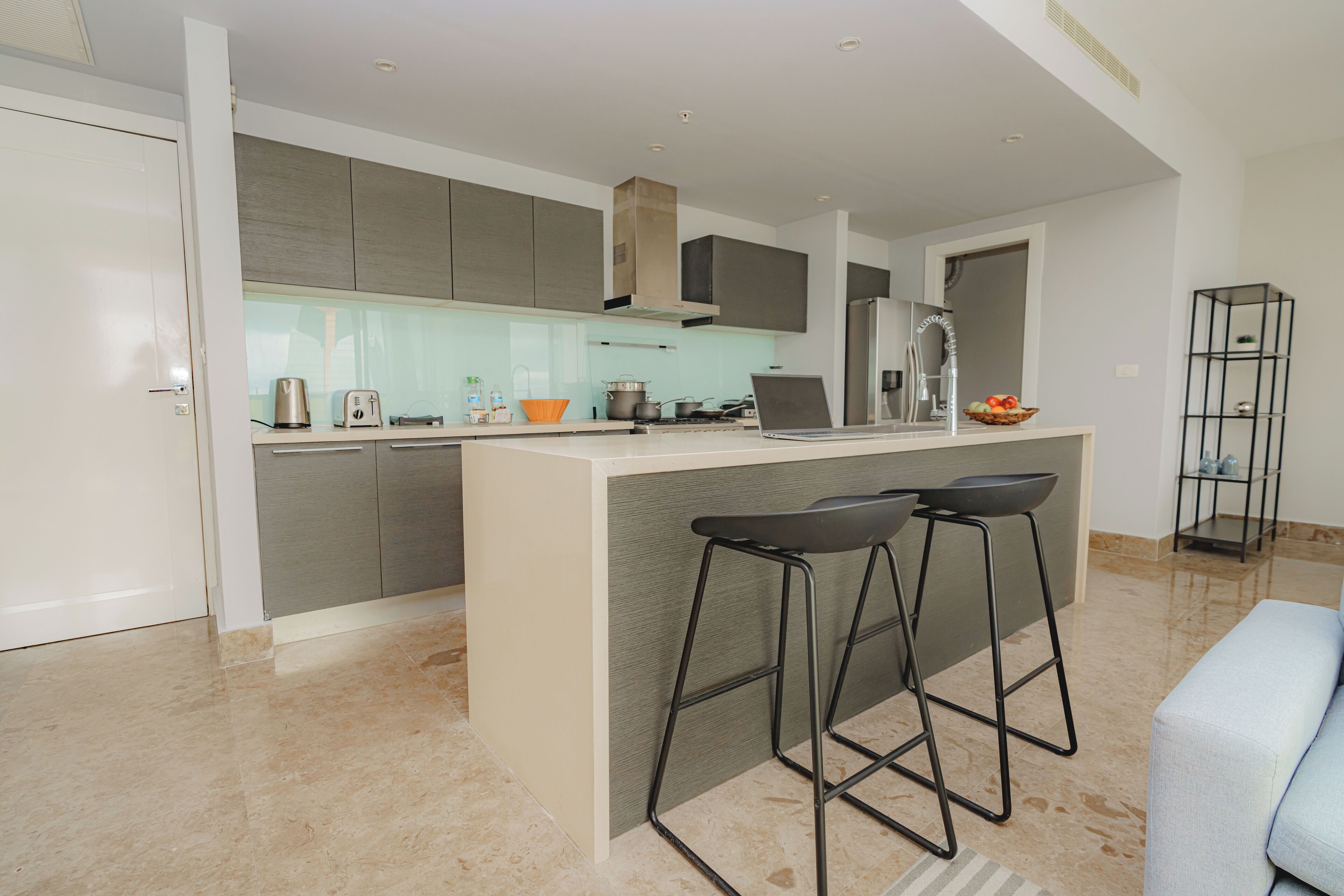 Una cocina moderna con una isla central, taburetes de bar y horno empotrado.