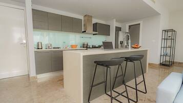 A modern kitchen with a central island, bar stools, and a built-in oven.