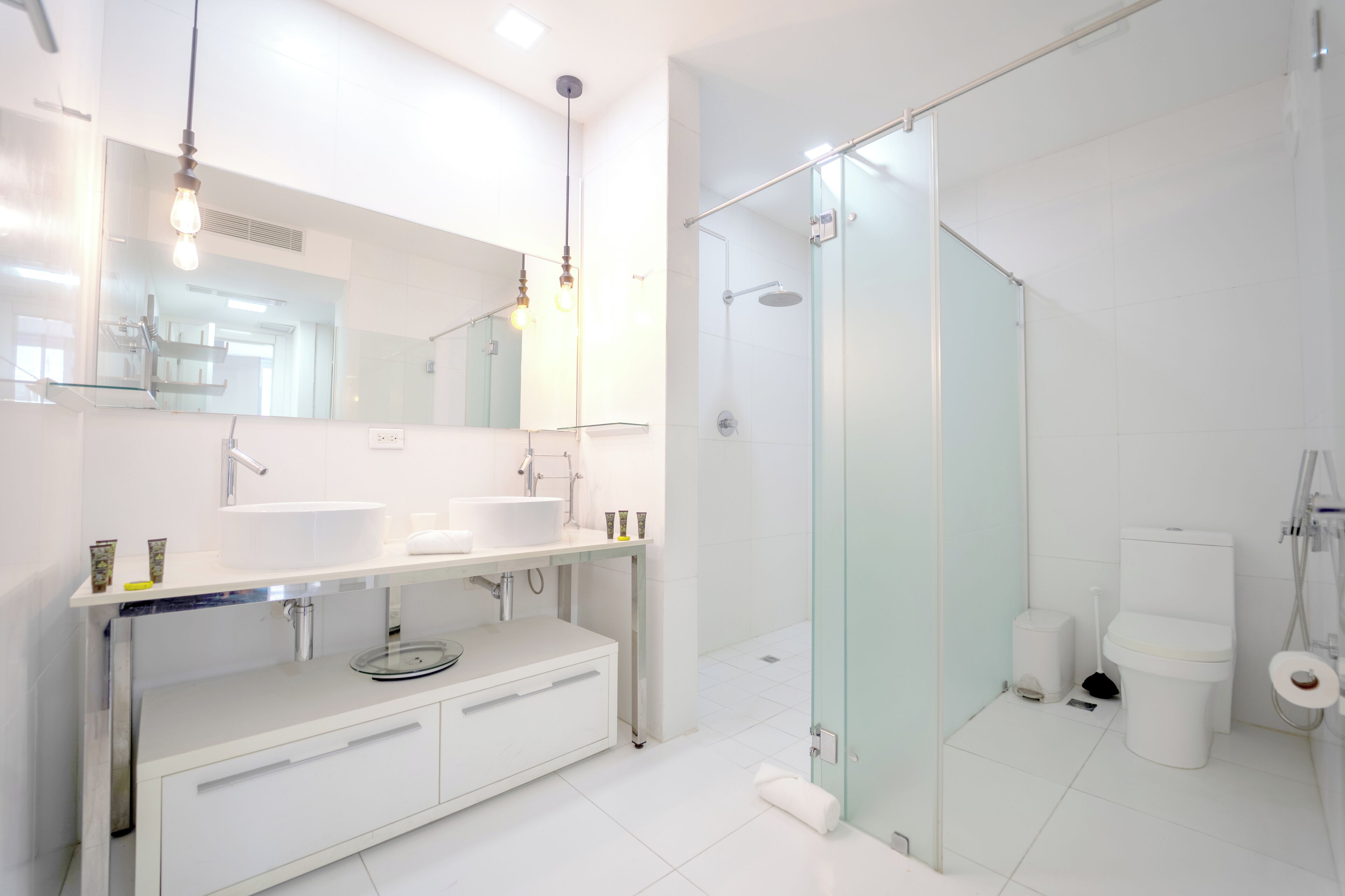 A modern bathroom with a glass-enclosed shower, a large mirror, and a white vanity with a sink and countertop.