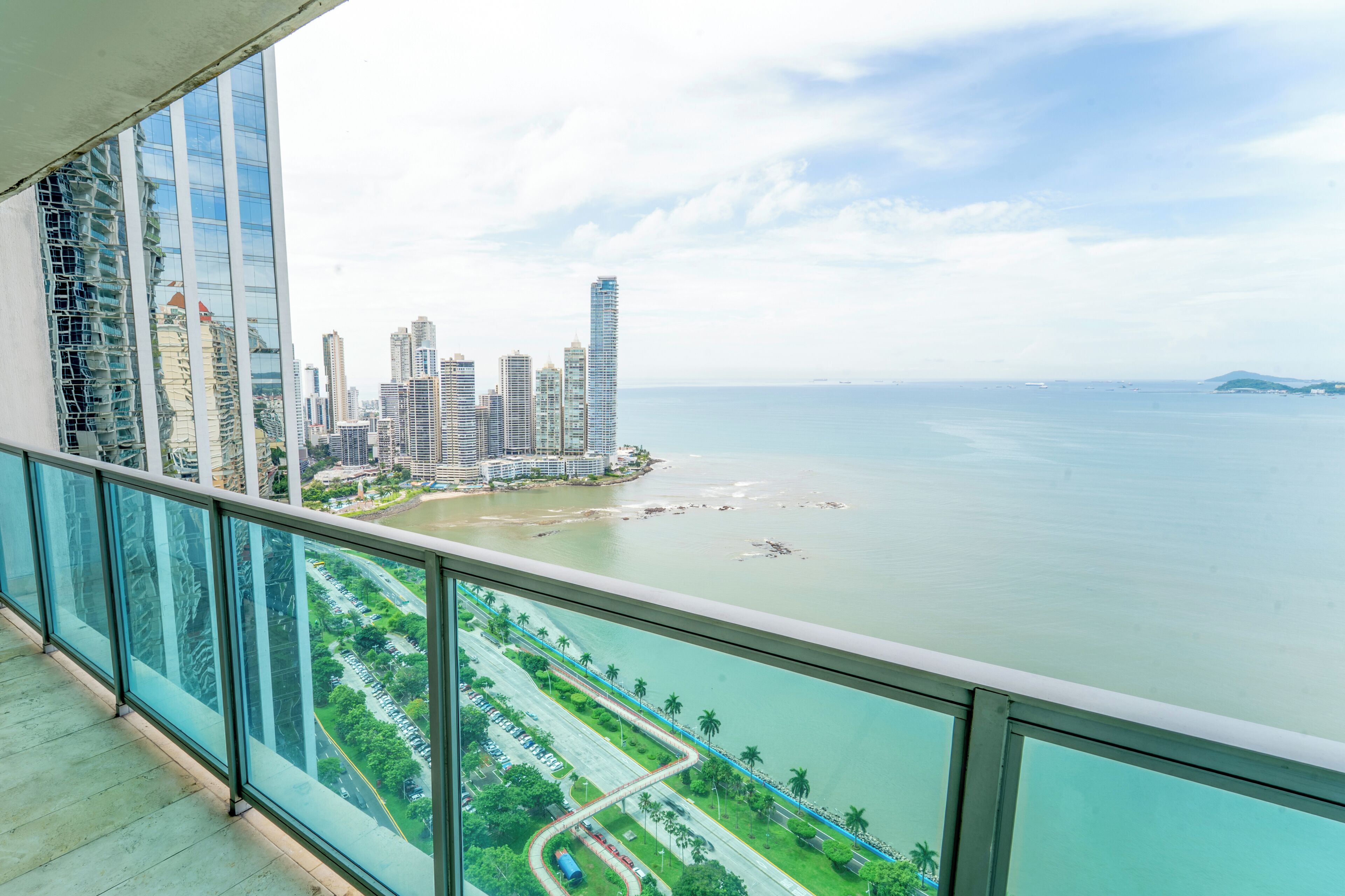 A high-rise building with a view of a coastal cityscape and a marina.
