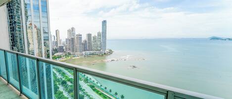 A high-rise building with a view of a coastal cityscape and a marina.