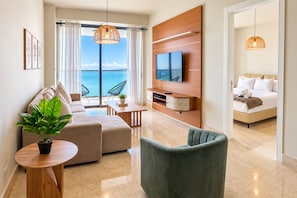Ein modernes Wohnzimmer mit einer Couch, Sesseln, einem Fernseher und Meerblick.