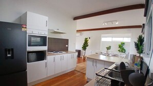 A modern kitchen with white cabinetry, a black refrigerator, and wooden flooring. - Capel Sound Hideaway (Capel Sound)