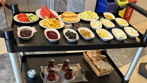 Ein Servicewagen mit einem reichhaltigen Frühstücksbuffet und verschiedenen Beilagen.