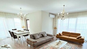 Ein geräumiges Wohnzimmer mit Essbereich, zwei Sofas, einem Couchtisch und einem Kronleuchter.