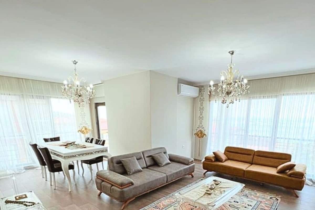 A spacious living room with a dining area, two sofas, a coffee table, and a chandelier.