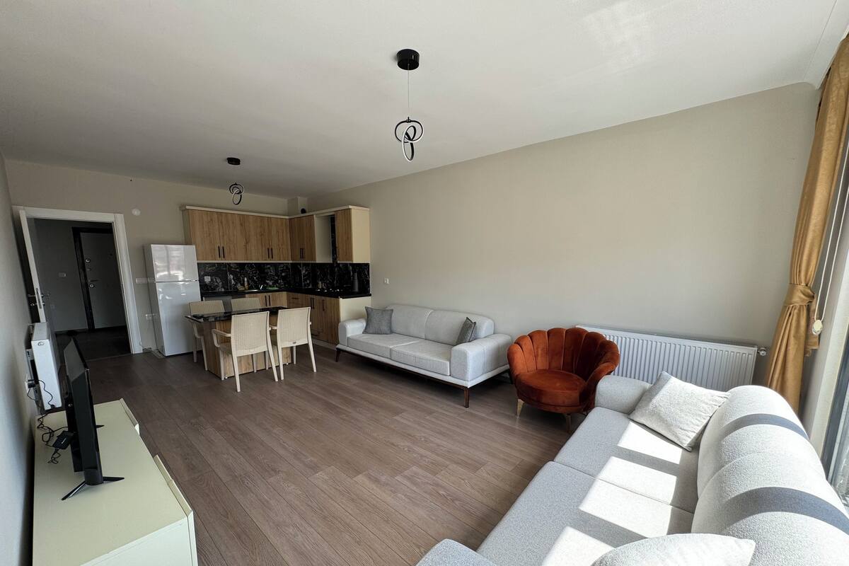 A modern living room with a sofa, armchair, and dining area.
