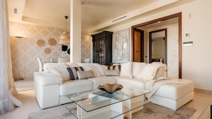 A modern living room with a white sectional sofa, a glass coffee table, and a large mirror. - Stylish Apartment With Pool in Marbella - Ref M51 (Marbella)