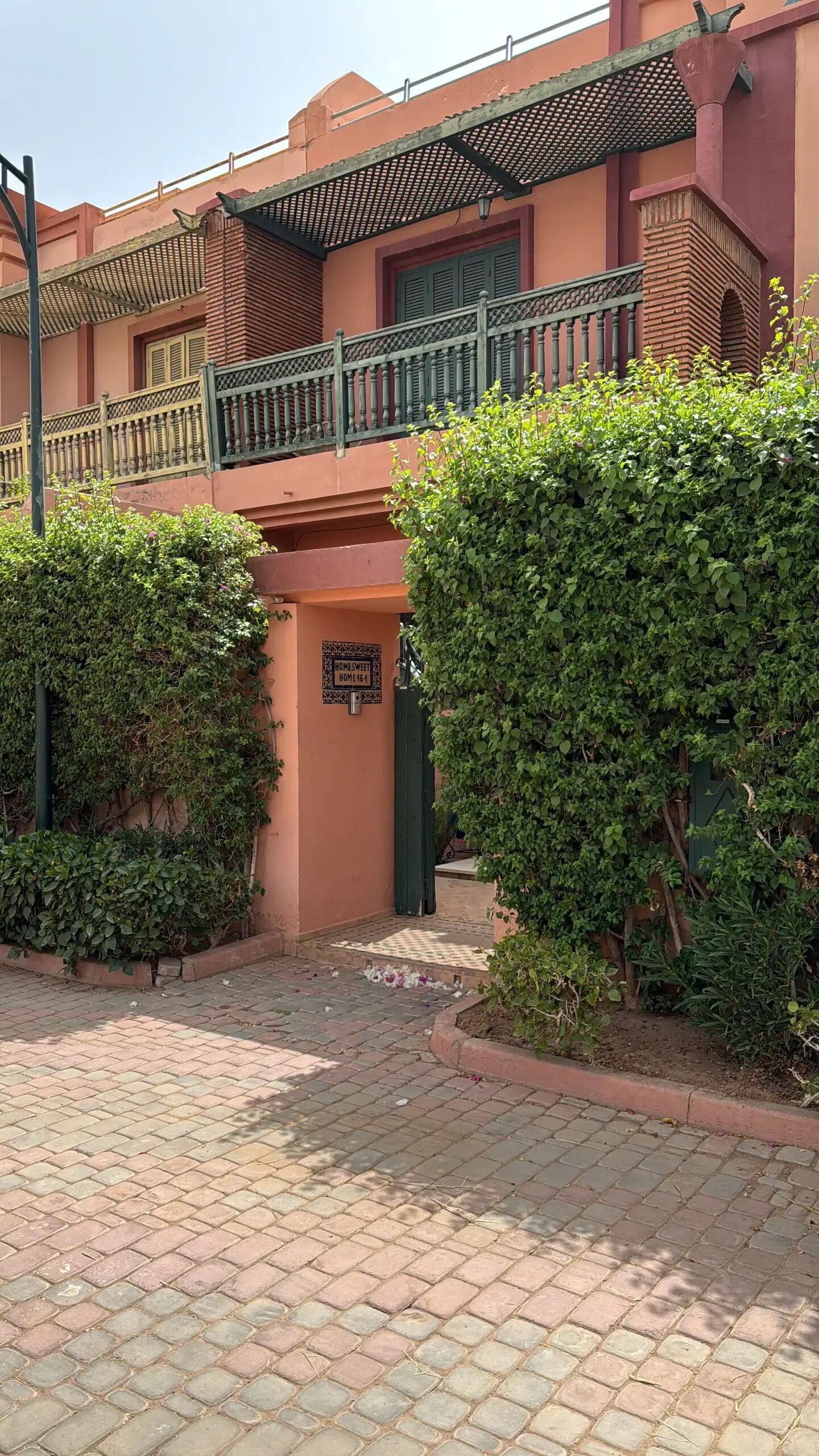 A building with a red facade, a green gate, and a sign that reads "HOMESWEET HOME4".