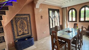 A spacious dining area with a large table and chairs, a decorative wall with intricate patterns, and a staircase with a unique design. - Vacation Riad with private pool 3 CH Hivernage (Marrakech)
