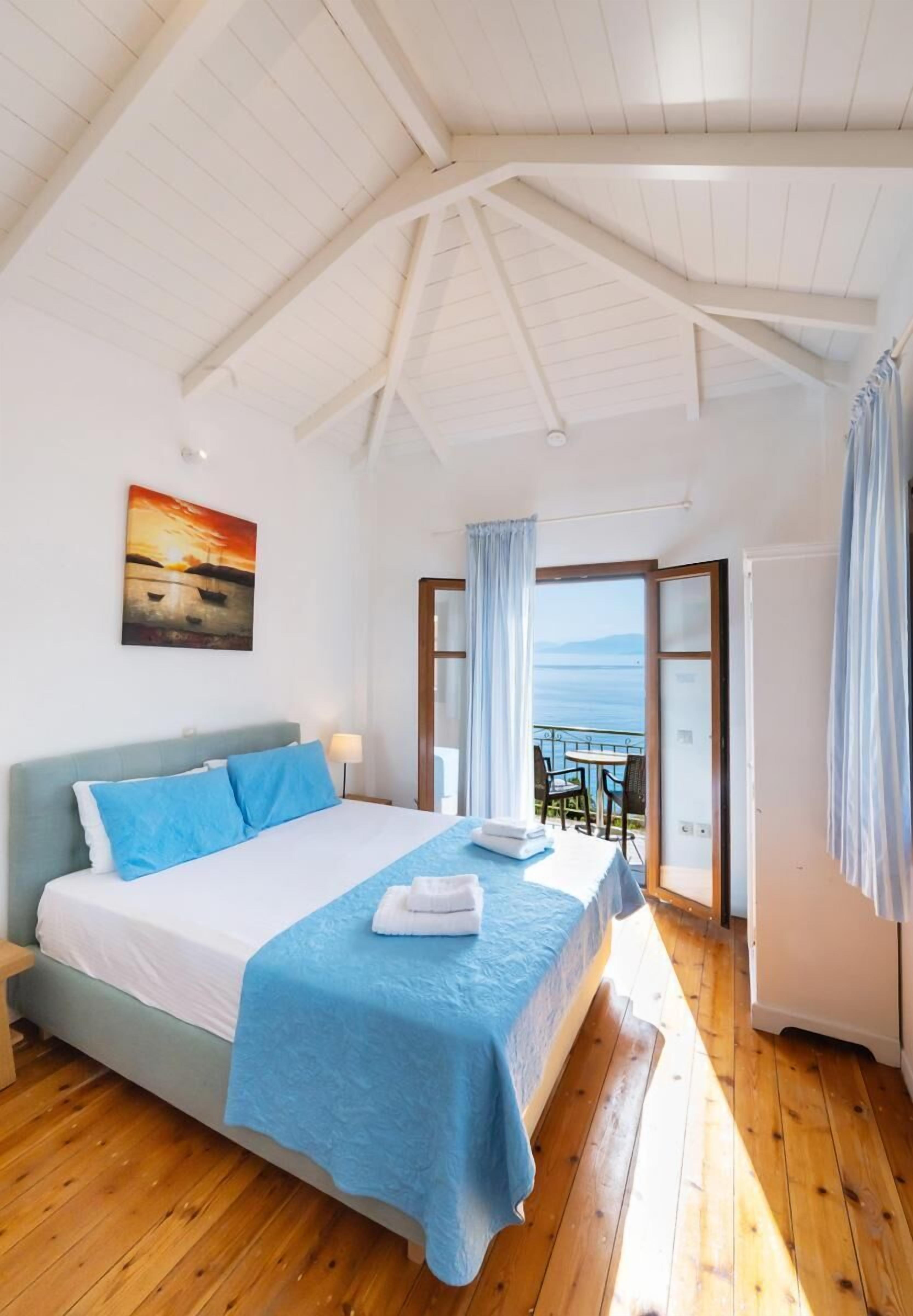 A bedroom with a large bed, a view of the sea, and a balcony.
