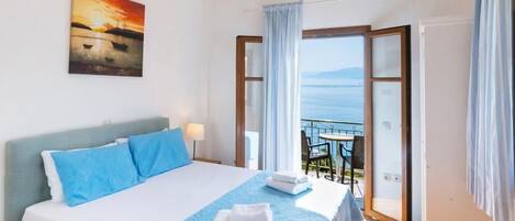 A bedroom with a large bed, a view of the sea, and a balcony.