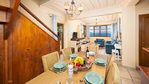 A dining area with a wooden table set for six, surrounded by wicker chairs. - Villa Pelagos Kyma - Two Bedroom Villa, Sleeps 4 (Lefkada)