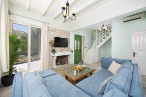 Una sala de estar con un conjunto de sofá, una chimenea, un televisor y una escalera.