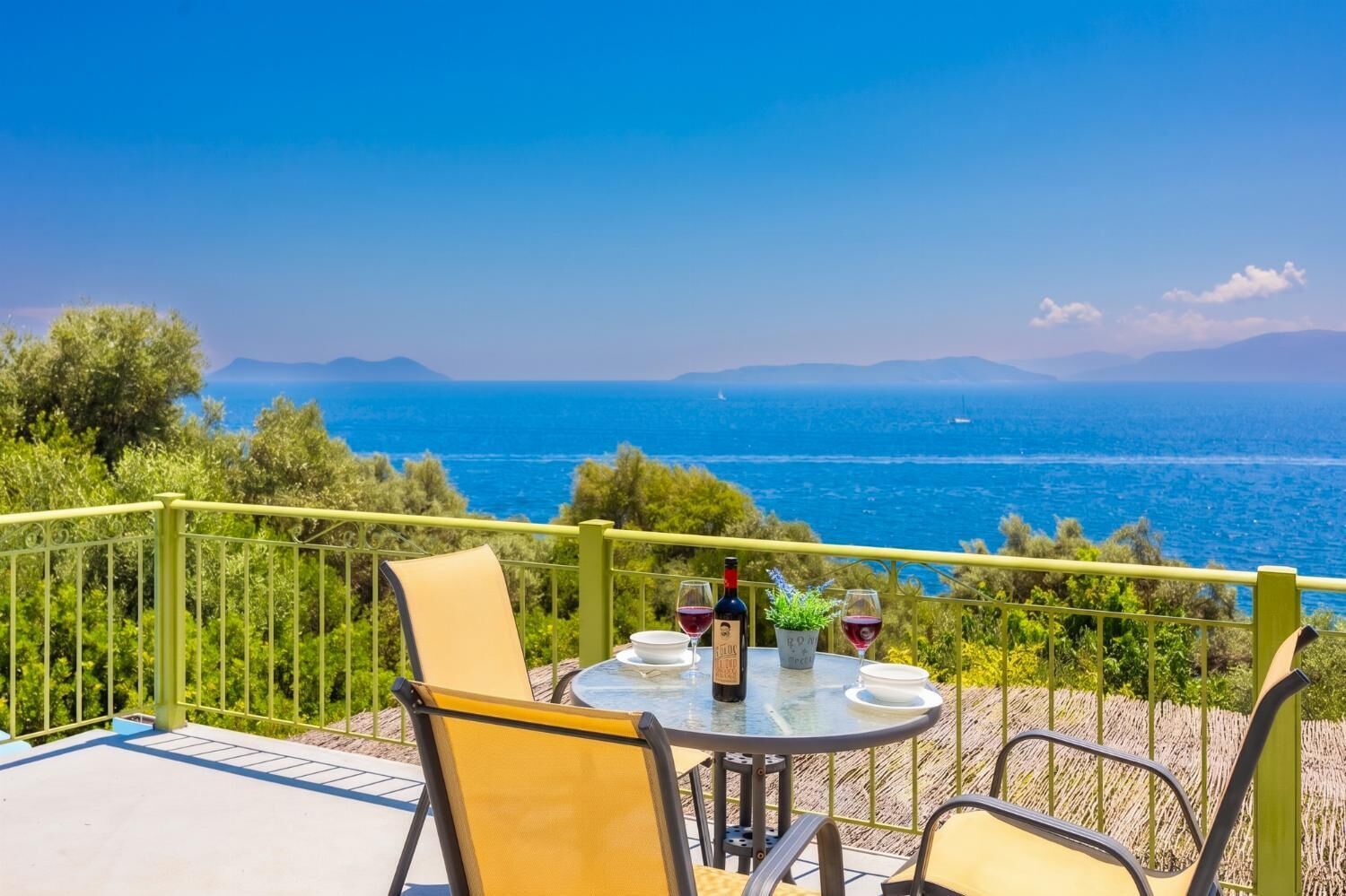 Une table entourée de chaises sur un balcon donnant sur la mer.