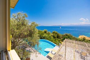 On aperçoit clairement une piscine, avec une vue sur la mer et un voilier au loin.