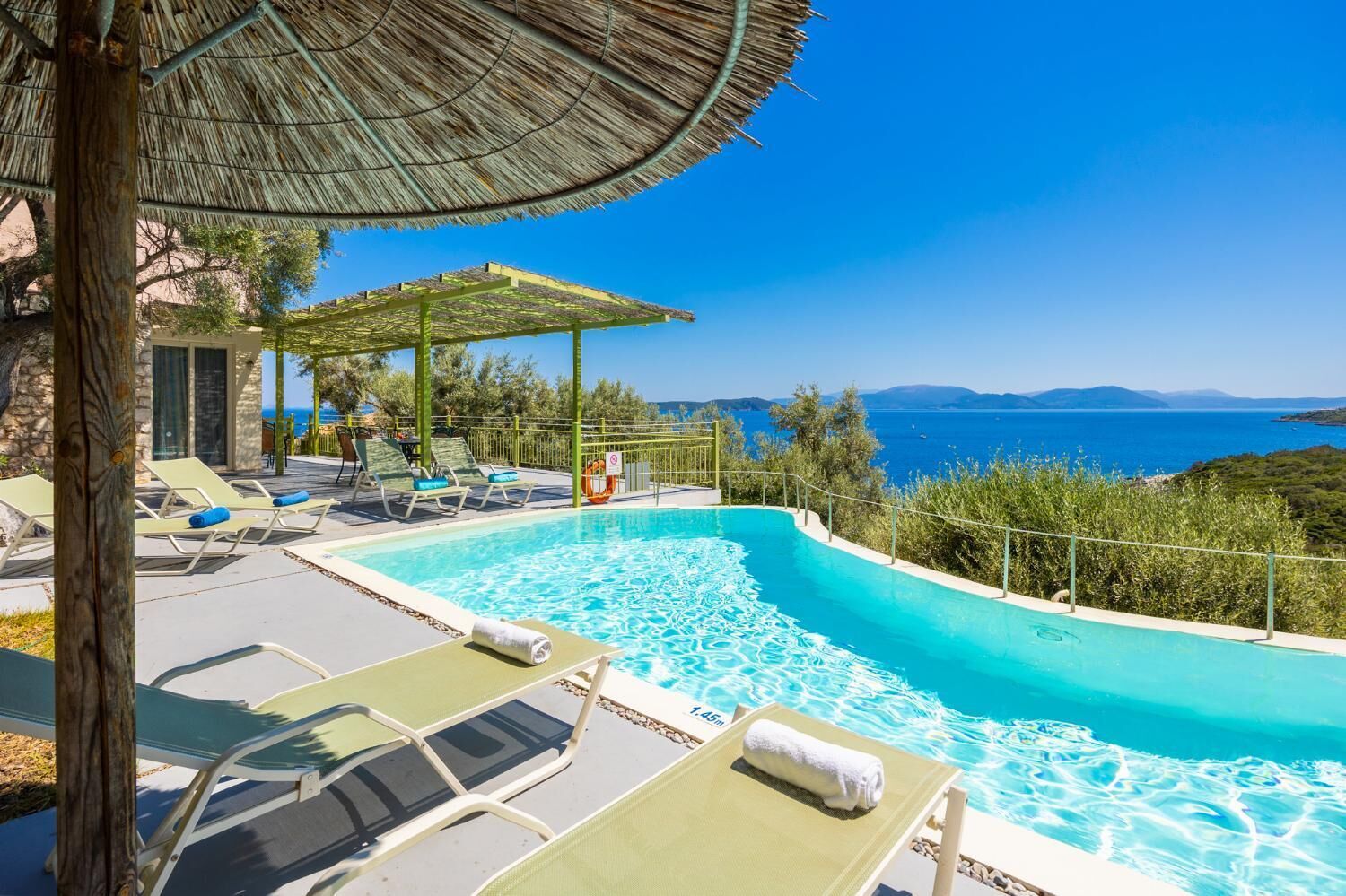 A pool area with lounge chairs and a view of the sea.