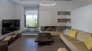 Ein modernes Wohnzimmer mit Flachbildfernseher, einer Couch, einem Couchtisch und einem Kamin.