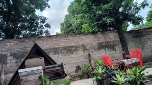 Un espacio de estar al aire libre rústico con muros de ladrillo, una estructura de madera y plantas en macetas.