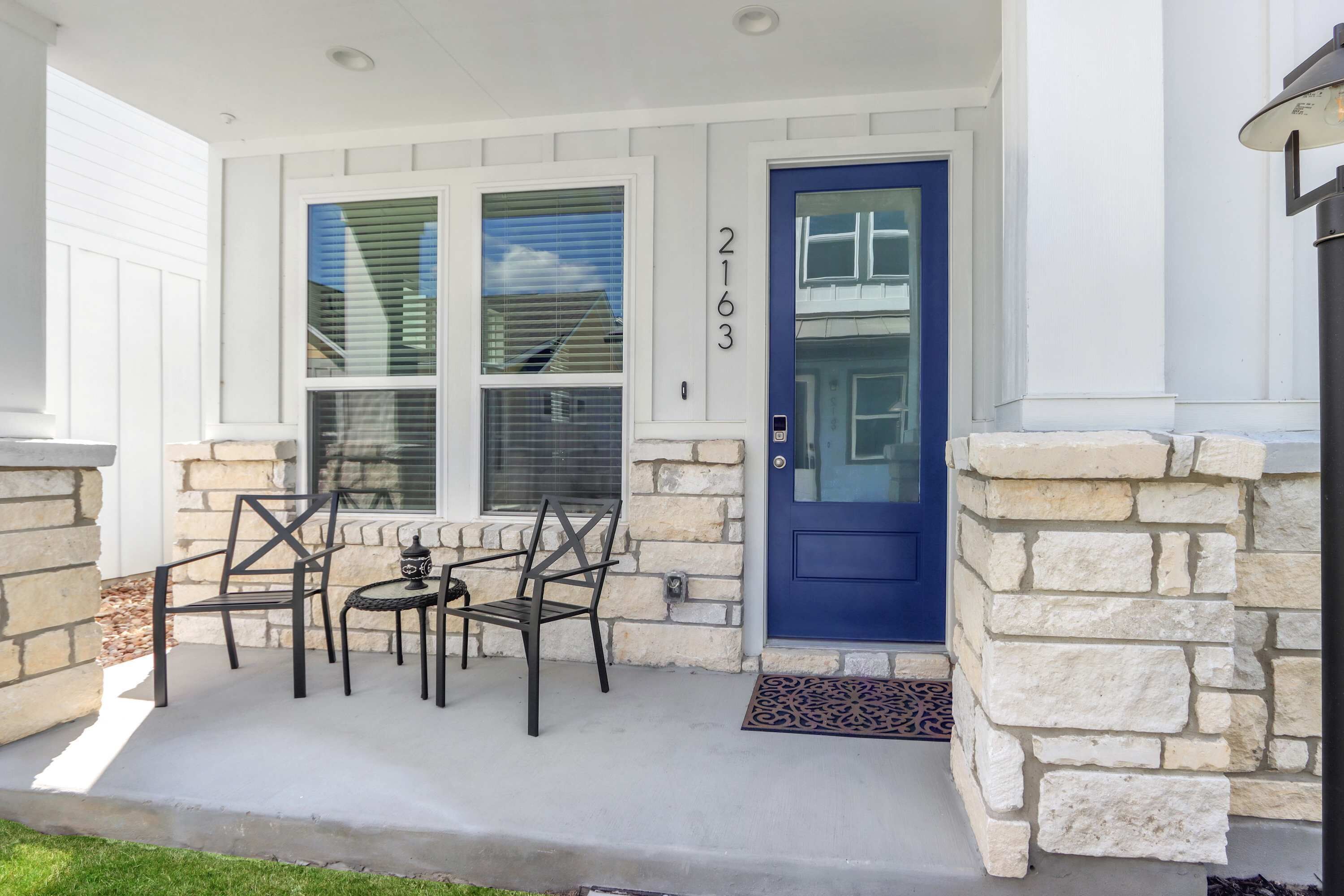 A front porch with a blue door, stone walls, and a small table with chairs.