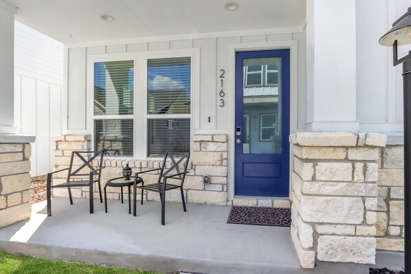 Un portico con una porta blu, pareti in pietra e un tavolino con sedie.